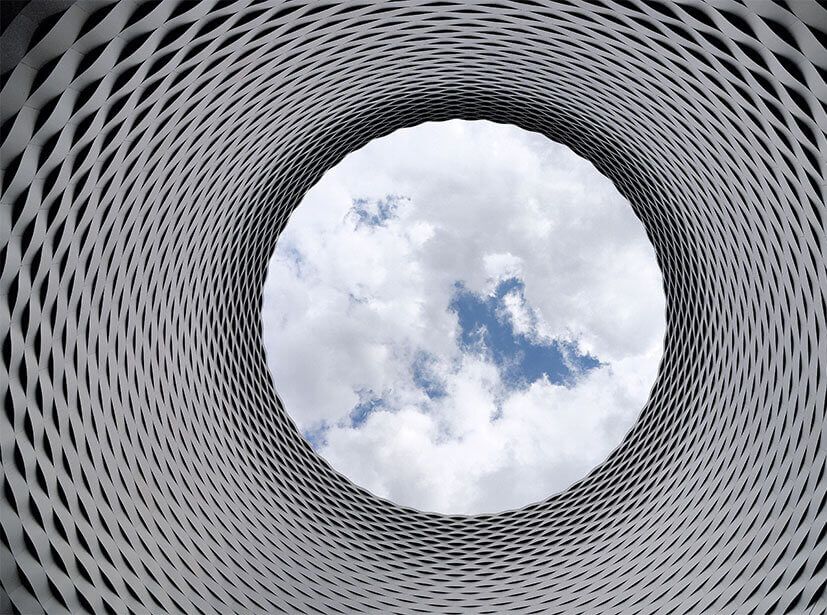 Looking up through a woven architectural canopy to the sky